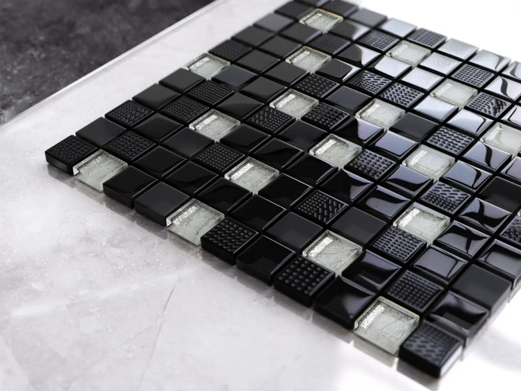 Glasmosaik mit quadratischen Steinchen in Schwarz und Silber, glänzende, matte und strukturierte Oberflächen.