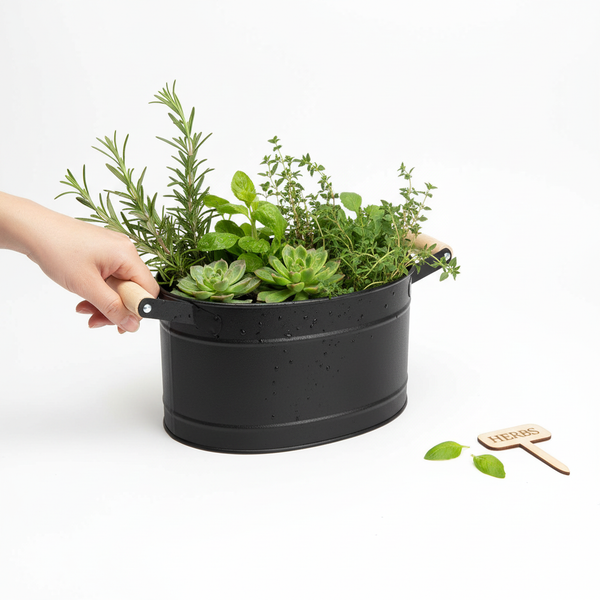 Schwarzer Kräutertopf aus Metall mit Holzgriffen, bepflanzt mit Kräutern wie Rosmarin und Minze.