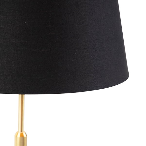 Nahaufnahme eines schwarzen Textillampenschirms auf einem goldfarbenen Lampengestell aus Metall.