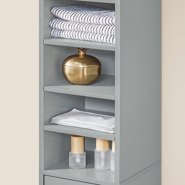 Detailansicht eines grauen Badezimmerschranks mit Handtüchern, Dekoration und Pflegeprodukten