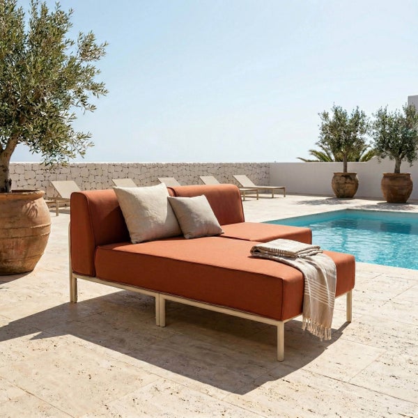 Modernes Terrassenambiente am Pool mit einer orangefarbenen Outdoor-Doppelliege aus Metall und Stoff sowie Olivenbäumen in Terrakottatöpfen.