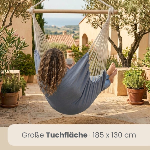 Blauer Hängesessel mit Holzstab und großer Tuchfläche von 185 mal 130 Zentimetern auf einer sonnigen Terrasse mit Pflanzen.