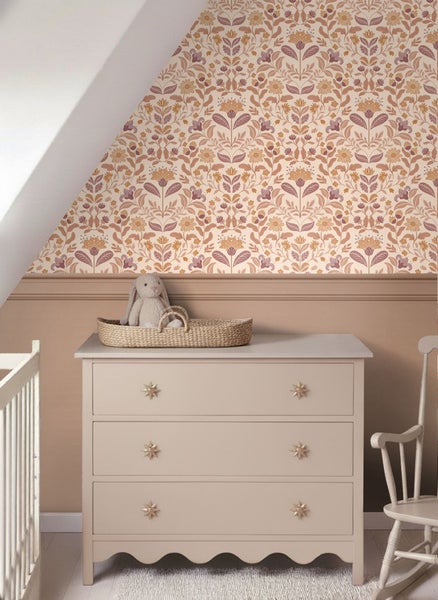 Kinderzimmer mit Kommode, Stofftier und floraler Tapete.