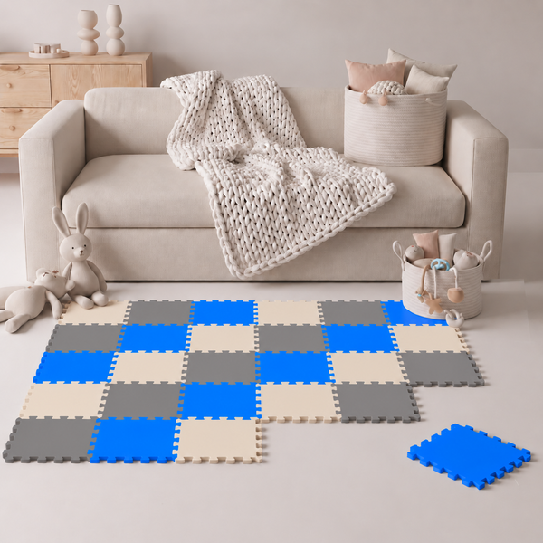 Spielmatte aus Schaumstoff in Puzzleoptik mit quadratischen Elementen in Blau, Grau und Beige für das Kinderzimmer vor einem Sofa.