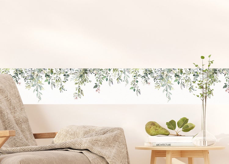 Selbstklebende Wandbordüre mit herabhängenden grünen Blättern und Eukalyptus-Motiv in einem hellen, modern eingerichteten Wohnzimmer.