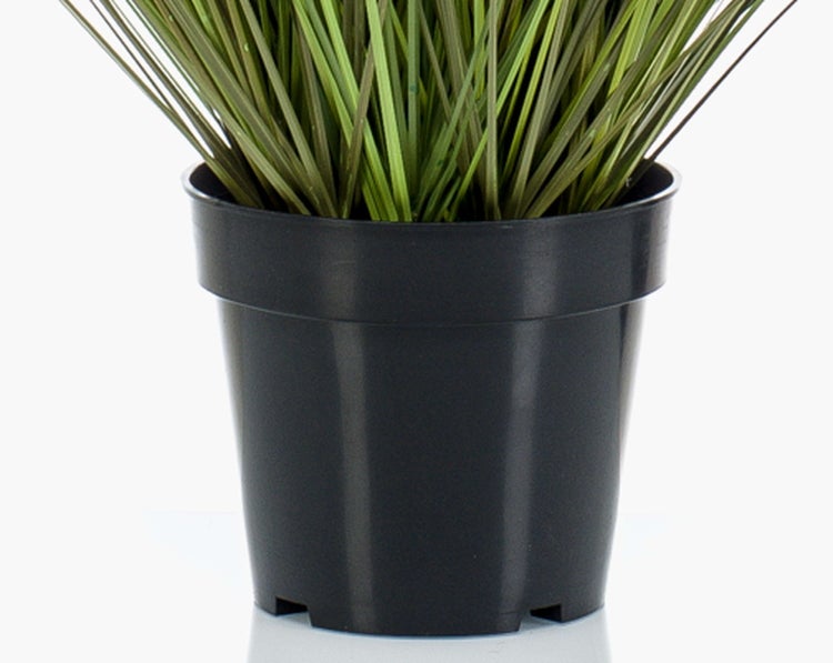 Künstliches Gras in einem schwarzen Kunststofftopf.