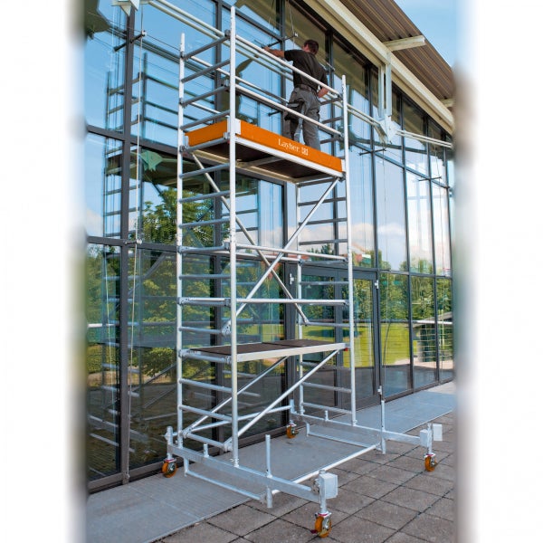 Fahrgerüst mit Arbeiter vor einem Gebäude mit Glasfassade