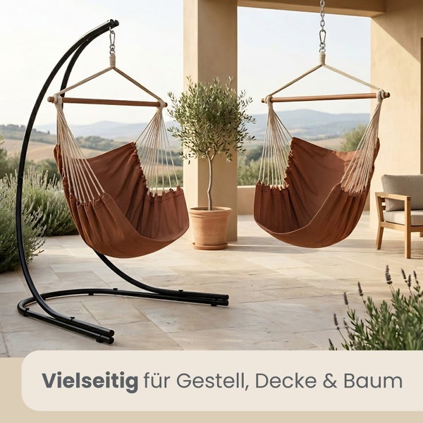Zwei braune Hängesessel aus Stoff mit Holzstab, einer an einem schwarzen Metallgestell und einer an der Decke auf einer hellen Terrasse.