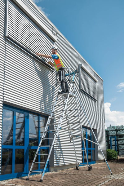 Mann arbeitet auf einer Zarges Treppe an einem Gebäude mit Metallfassade