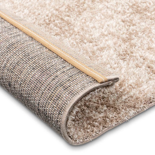 Nahaufnahme eines Hochflor-Teppichs mit weicher Oberfläche, gewebter Rückseite und verstärkter Kante.