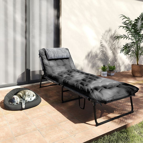 Moderne Gartenliege mit dicker Polsterung und Kopfkissen auf einer sonnigen Terrasse mit Fliesen und Pflanzen.