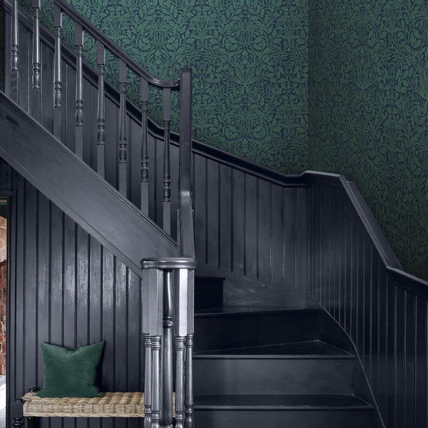 Treppenhaus mit dunkler Holztreppe und floraler Tapete