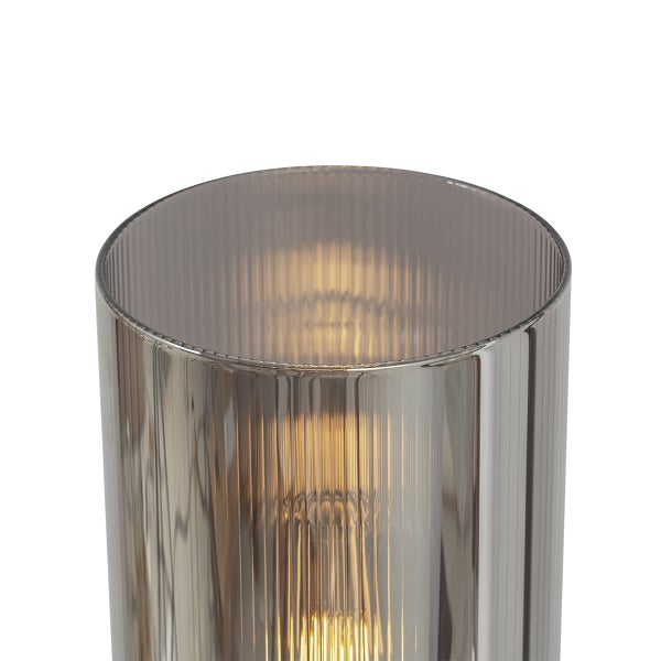 Zylindrischer Lampenschirm aus rauchgrauem Glas mit geriffelter Struktur und leuchtendem Leuchtmittel.