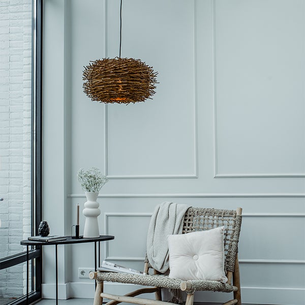 Dekoratives Wohnzimmer mit einer Hängelampe in Vogelnesterform über einem Sessel mit Kissen