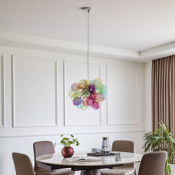 Moderner Essbereich mit einer bunten Pendelleuchte aus Glaskugeln über einem runden Marmortisch in einem hellen Raum mit Wandpaneelen.