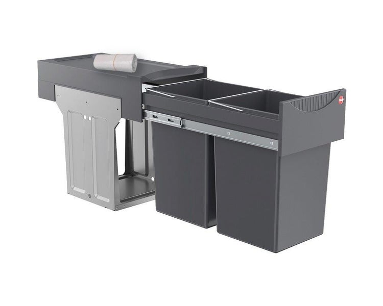Ausziehbarer Einbaumüllsammler mit zwei grauen Abfalleimern, Metallrahmen und Ablagefläche für Müllbeutelrollen.