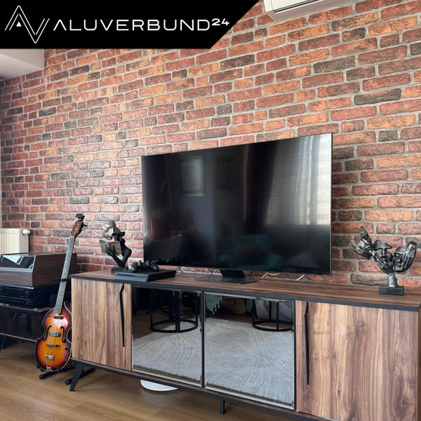 Wohnzimmer mit Steinwand, modernem Sideboard und elektronischen Geräten
