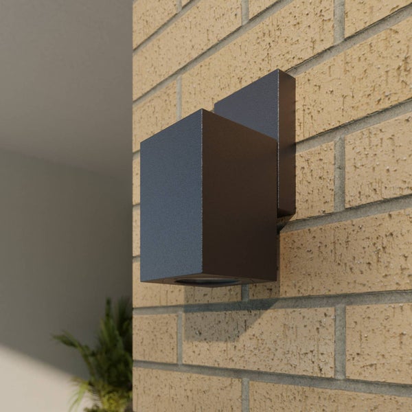 Moderne quadratische Außenwandleuchte aus anthrazitfarbenem Metall, montiert an einer Ziegelwand.