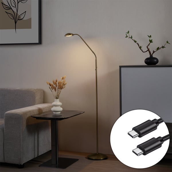 Moderne Stehleuchte aus Messing mit flexiblem Arm neben einem Sofa im Wohnzimmer. Ein runder Ausschnitt zeigt zwei USB-C-Stecker.