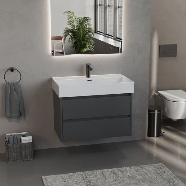 Modernes Badezimmer mit anthrazitfarbenem Waschtischunterschrank, weißem Waschbecken und hinterleuchtetem Spiegel.