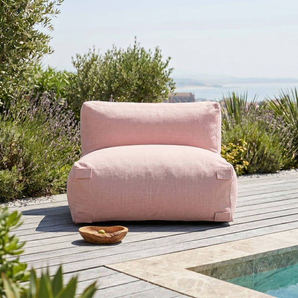 Rosa Outdoor-Lounge-Sessel aus Stoff auf einer Holzterrasse neben einem Pool, umgeben von grünen Pflanzen und Lavendel.