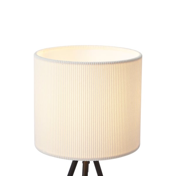 Zylindrischer Lampenschirm in Cremeweiß mit gerippter Stoffstruktur auf einem dreibeinigen Stativfuß.