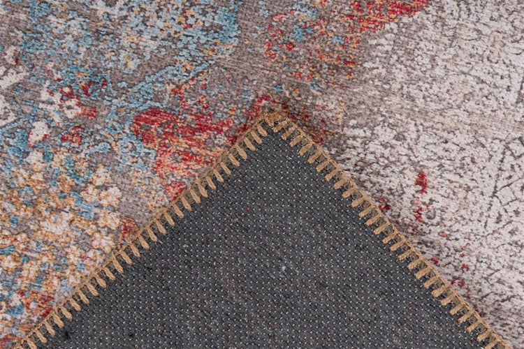 Detailansicht eines Teppichs mit buntem Muster auf der Vorderseite und dunkelgrauer Unterseite mit Kettelrand.