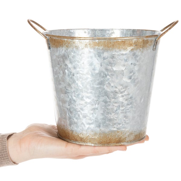 Verzinkter Metalleimer mit zwei Griffen und rustikalem Rand, zur Größendarstellung in einer Hand gehalten.