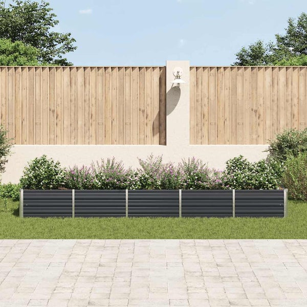 Moderner Garten mit einem langen, anthrazitfarbenen Hochbeet aus Metall, bepflanzt mit Blumen vor einem Holzzaun und einer hellen Wand.