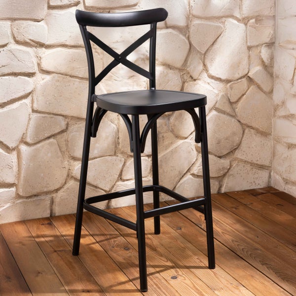 Schwarzer Barhocker mit Crossback-Rückenlehne und Fußstütze vor einer Steinwand auf Holzboden.