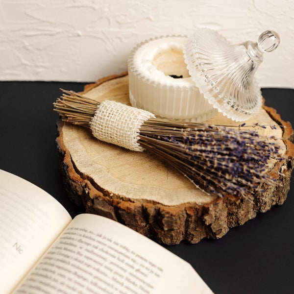 Hängende Holzkiste als Pflanzgefäß in Weiß mit dicken Juteseilen und einer grünen Pflanze.
