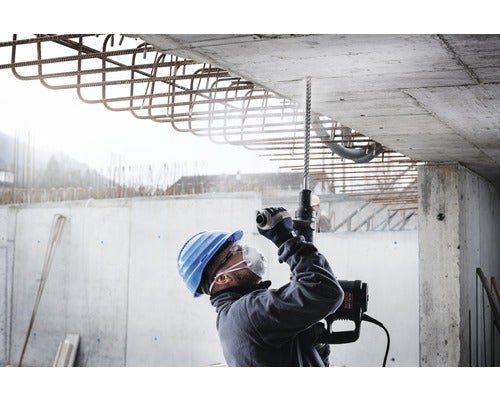 Mann bohrt mit Bohrhammer in Betonkonstruktion auf einer Baustelle