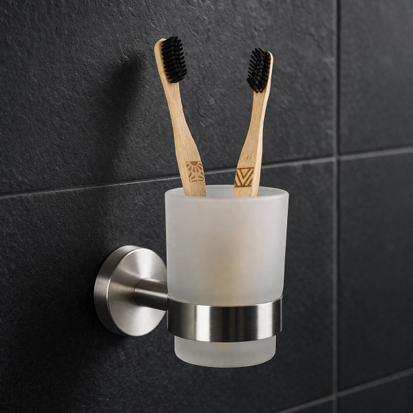 Wand-Zahnbürstenhalter aus Edelstahl mit einem Becher aus satiniertem Glas und zwei Zahnbürsten aus Bambus.