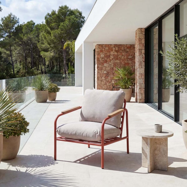 Moderner Loungesessel mit Metallgestell, Holzarmlehnen und Polstern auf einer hellen, geräumigen Terrasse mit Steinwand und Pflanzen.