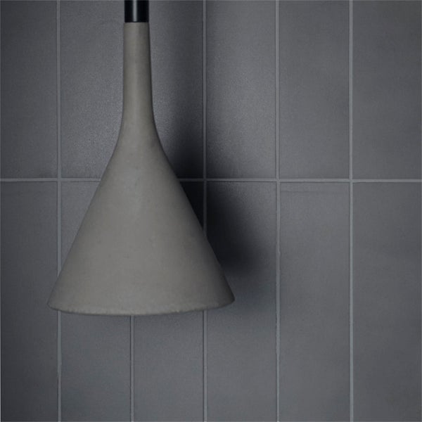 Wand mit rechteckigen Fliesen im Hochformat und einer hängenden Lampe mit konischem Lampenschirm.