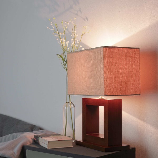 Dekorative Tischleuchte mit rechteckigem Schirm auf einem Nachttisch mit Buch und Vase.