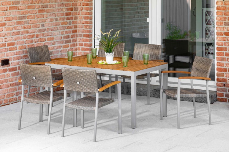 Garten-Essgruppe auf einer Terrasse mit einem rechteckigen Tisch aus Holz und Metall sowie sechs Stühlen aus Geflecht mit Holzarmlehnen.