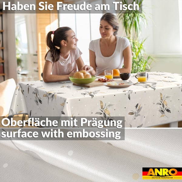 Tischdecke mit Blättermotiv und geprägter Oberfläche in einer hellen Esszimmer-Szene mit zwei Personen beim Frühstück. ANRO Logo.