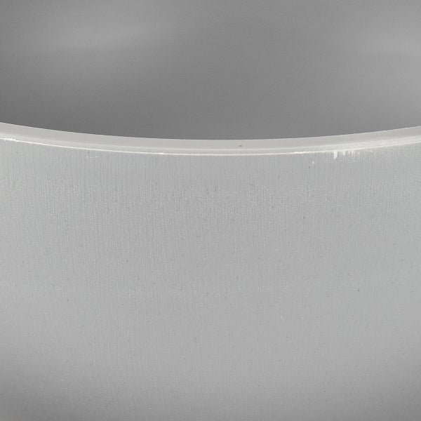 Detailansicht der strukturierten Oberfläche und des Randes eines runden grauen Pflanztopfes.