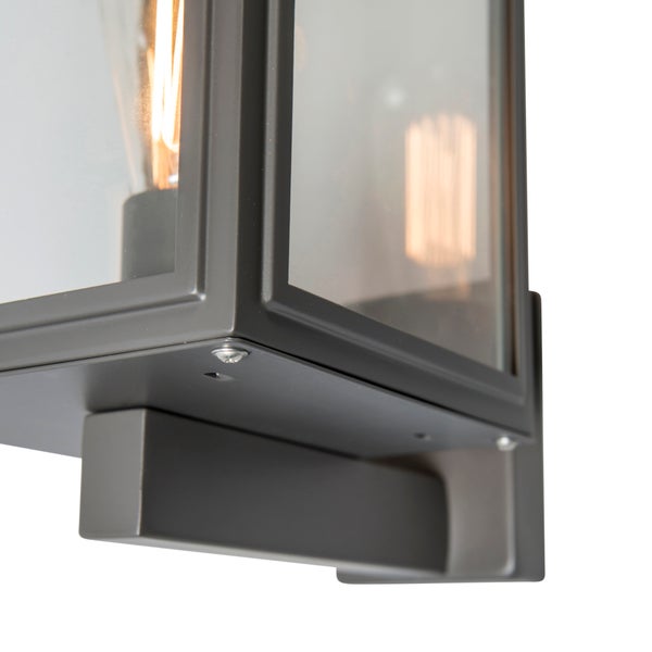 Detailansicht einer modernen Wandleuchte aus Metall und Glas mit leuchtendem Filament-Leuchtmittel.
