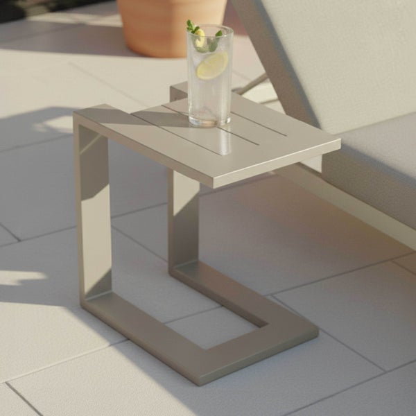 Beistelltisch in C-Form aus Metall für Garten und Terrasse neben einer Sonnenliege.