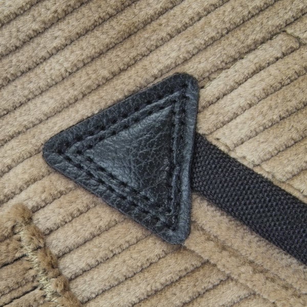 Detailaufnahme von Cordstoff mit einem dreieckigen Leder-Patch und einem Gurtband.