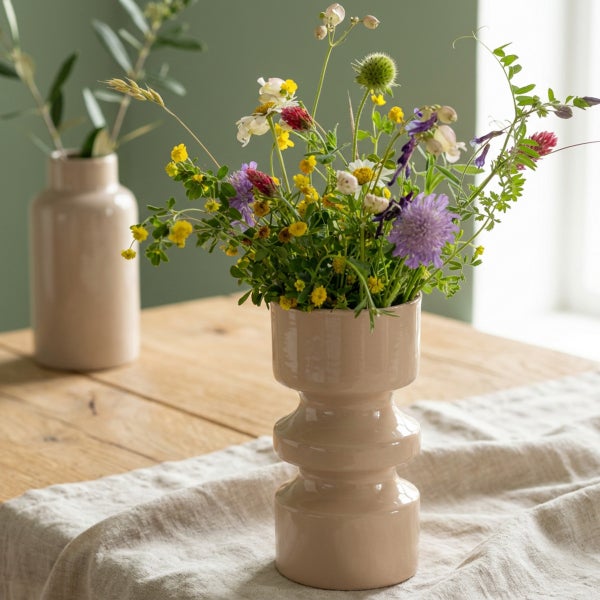 Zwei moderne Keramikvasen auf einem Holztisch mit einem bunten Blumenstrauß, der eine helle und natürliche Atmosphäre erzeugt.