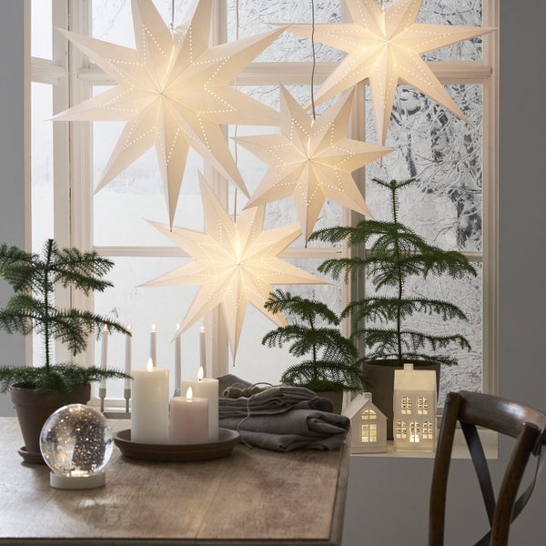 Dekorativer Tisch mit beleuchteten Sternen, Mini-Weihnachtsbäumen und LED-Häusern für eine festliche Atmosphäre.