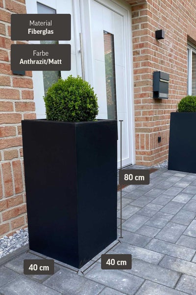 Hoher quadratischer Pflanzkübel aus Fiberglas in Anthrazit matt, Maße 40 mal 40 mal 80 Zentimeter, vor einem Hauseingang.