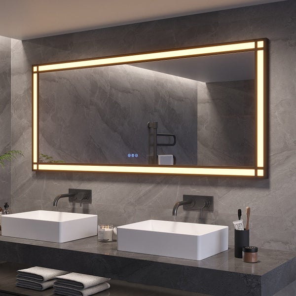 Großer Badezimmerspiegel mit integrierter LED Beleuchtung und Touch Steuerung über zwei Waschbecken an einer Wand mit dunklen Fliesen.
