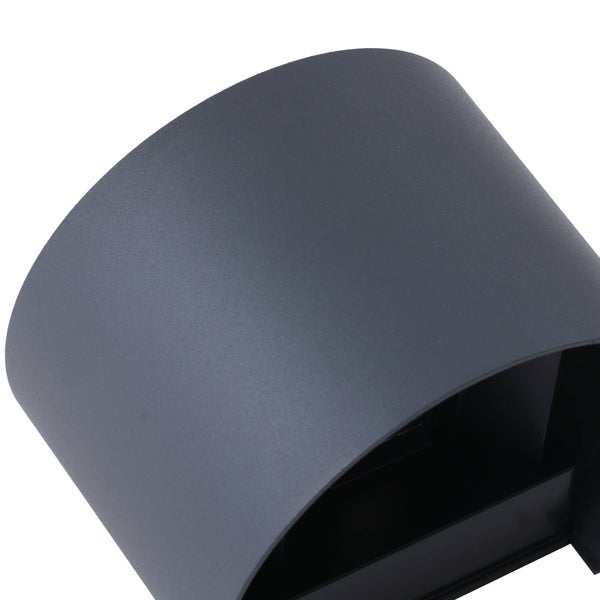 Moderne schwarze Außenwandleuchte mit Lichtkegeln nach oben und unten an einer strukturierten Fassade neben einer Tür.