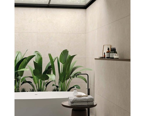 Helles Badezimmer mit Badewanne, Pflanzen und beigen Wandfliesen