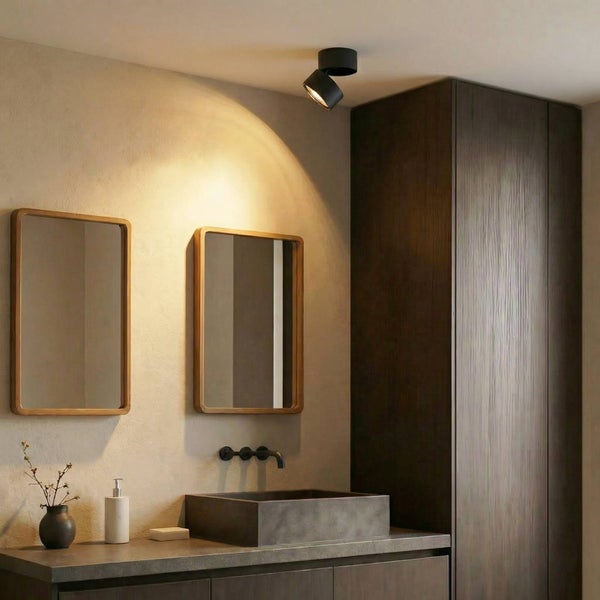 Modernes Badezimmer mit schwarzem Deckenstrahler, zwei Holzspiegeln, einem dunklen Steinwaschbecken, schwarzer Armatur und dunklem Holzschrank.