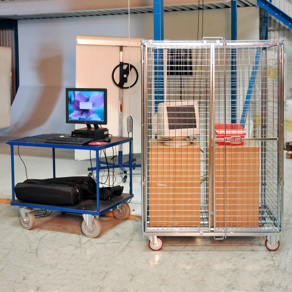 Rollwagen mit Computern und ein Gitterwagen in einer Lagerhalle